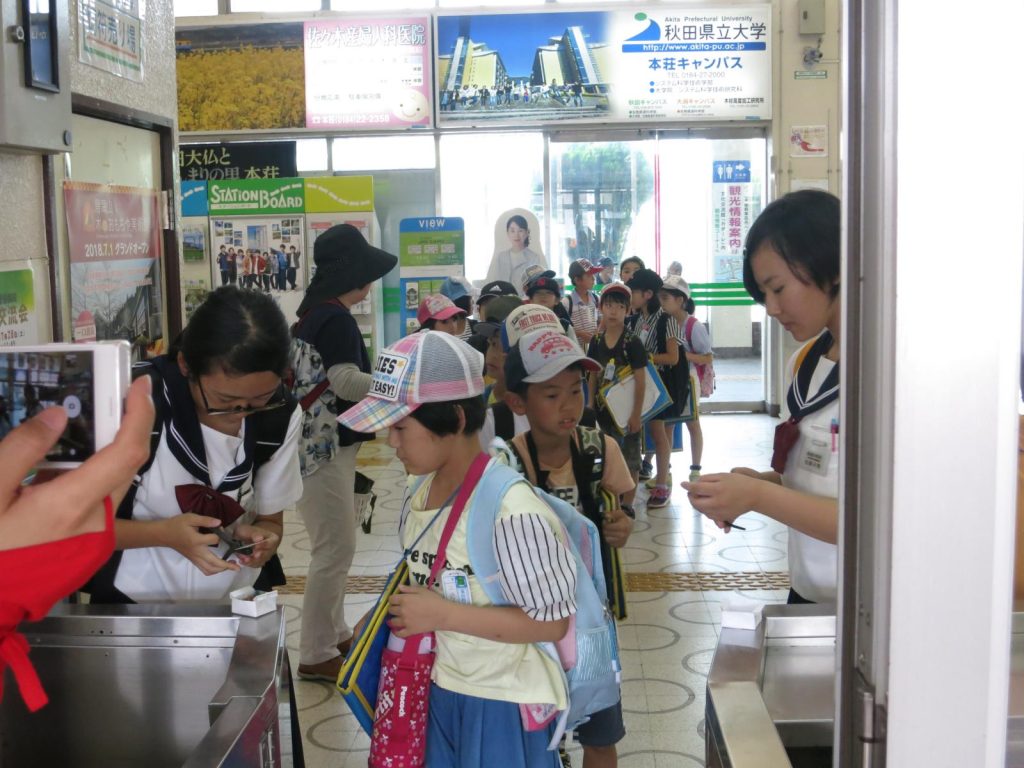写真：羽後本荘駅から，由利高原鉄道のおばこ号に乗り出発する児童の様子